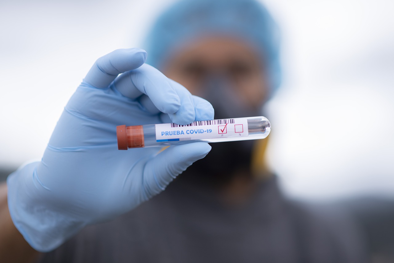 Blurred surgeon holding up glass vial labeled COVID-19